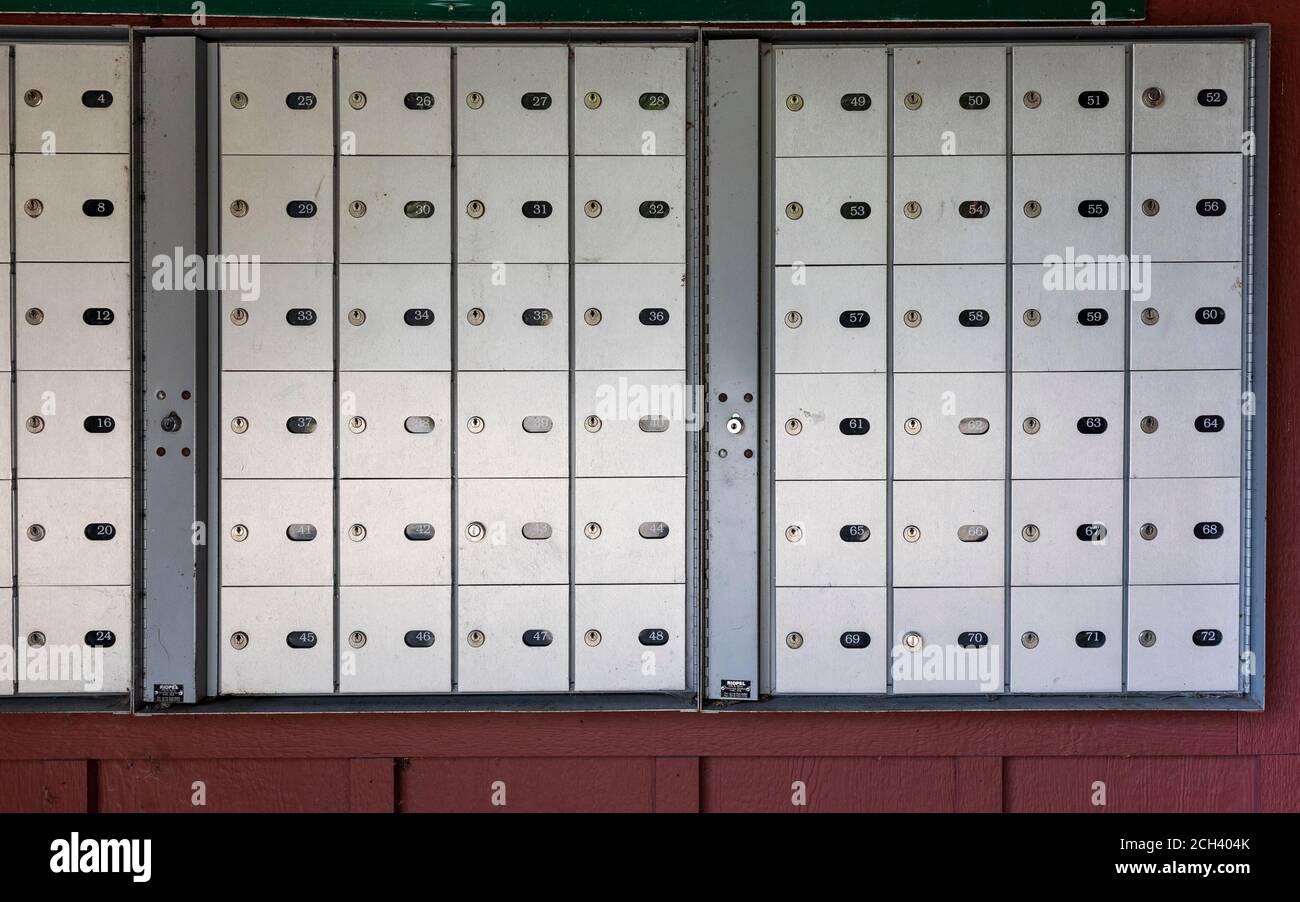 File di scatole di lettere in metallo bloccate appese sulla parete marrone nel complesso cittadino Foto Stock