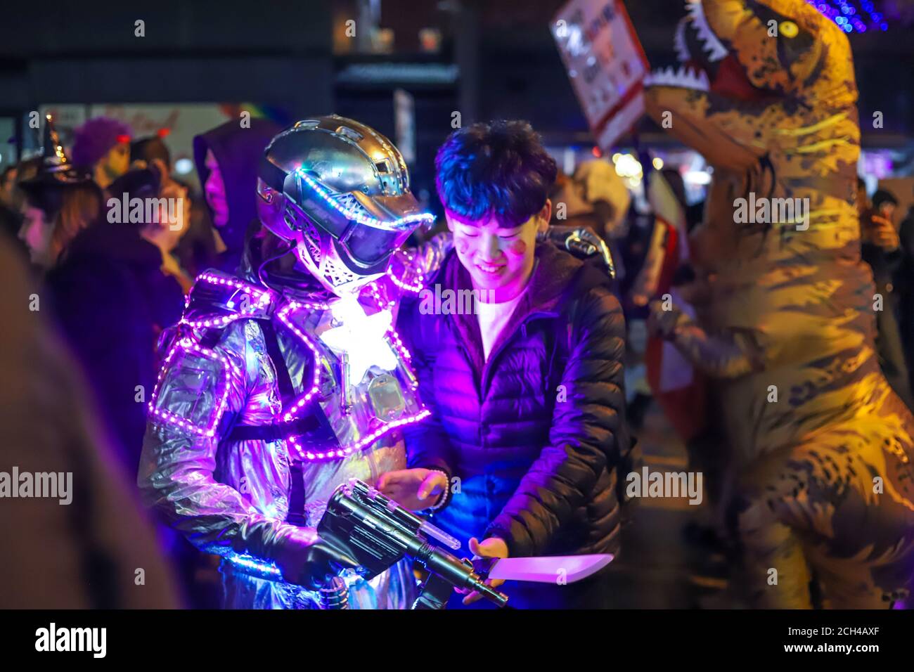 Halloween notte carnevale . Chiesa strada, persone che camminano in maschere e costumi diversi. Foto Stock