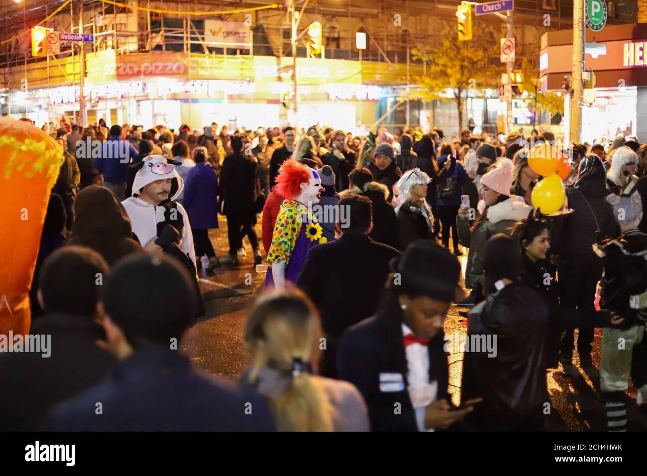 Halloween notte carnevale . Chiesa strada, persone che camminano in maschere e costumi diversi. Foto Stock