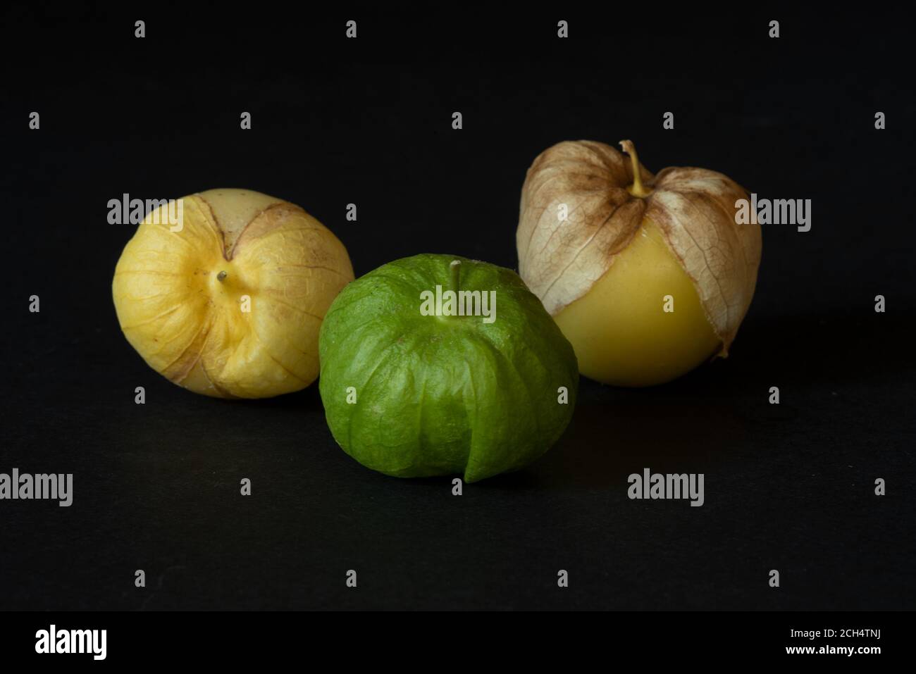 Tomatillos gialli e verdi non lavati su sfondo nero, visti da angolo di cena- concetto di produzione californiana Foto Stock