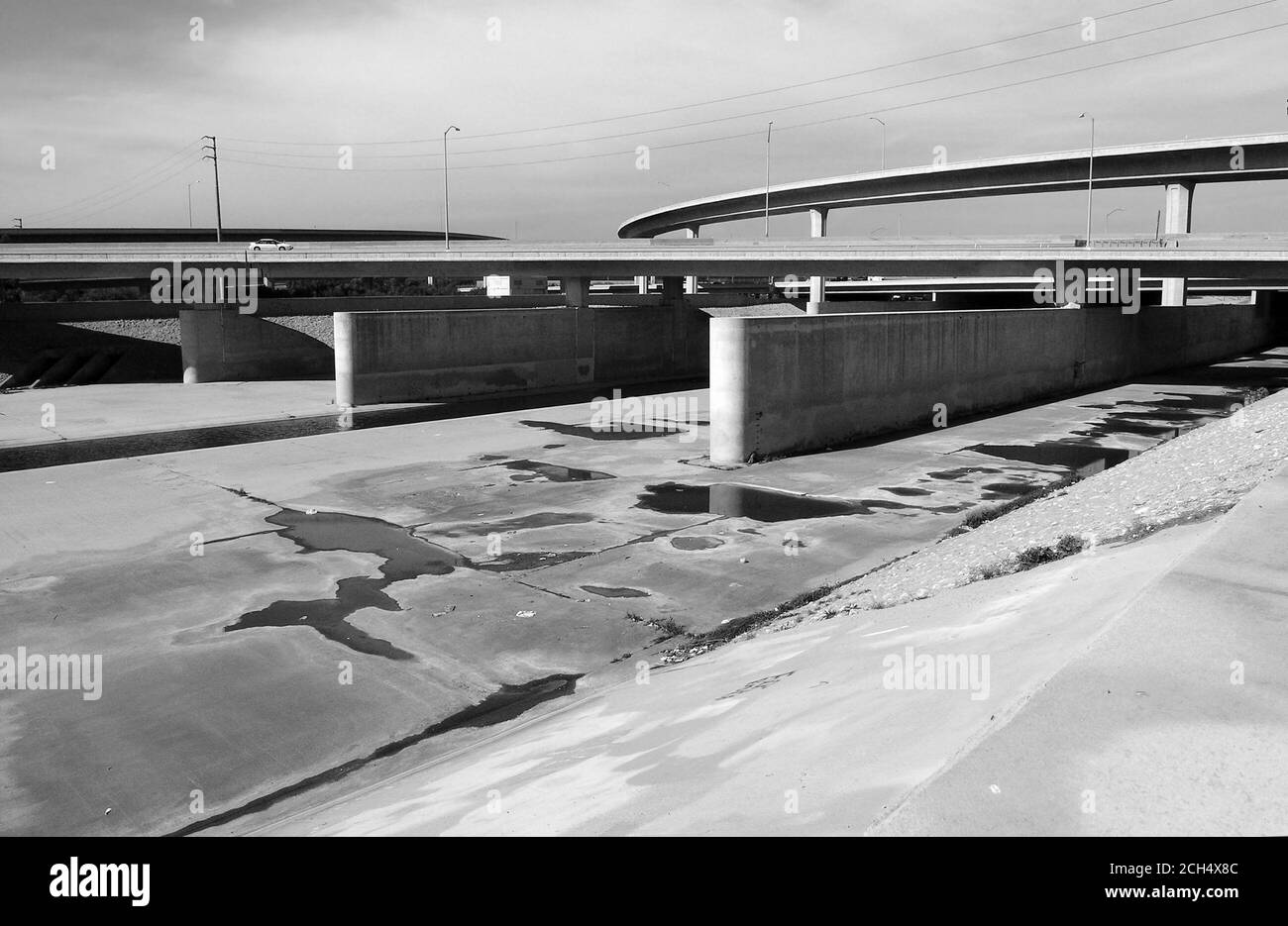 Vista archivistica in bianco e nero sul fiume Los Angeles, fiancheggiato da cemento, vicino alla superstrada 105 nella California meridionale. Foto Stock