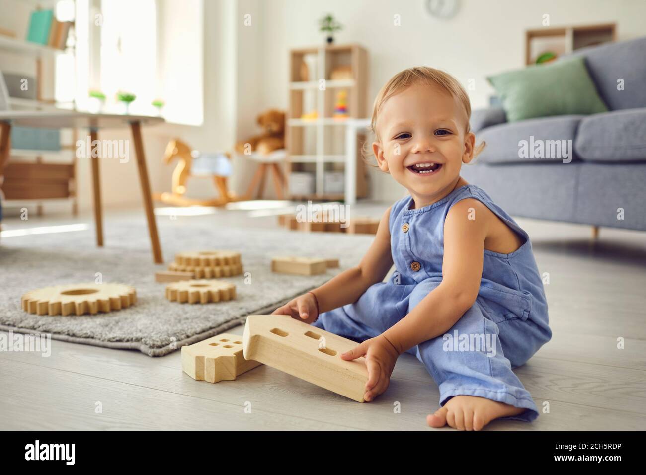 Carino ragazzino guardando la macchina fotografica sorridente felice durante il gioco in accogliente stanza per bambini Foto Stock