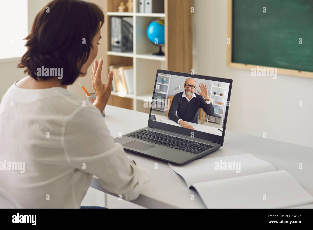 Formazione didattica online. L'insegnante femminile saluta lo studente universitario maschile senior utilizzando la videochiamata online con il laptop. Foto Stock
