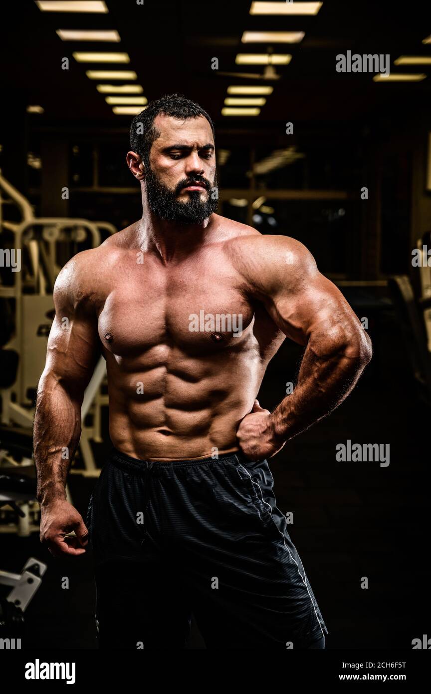 bel giovane atleta con un corpo forte e muscoloso in palestra di sport scuro Foto Stock