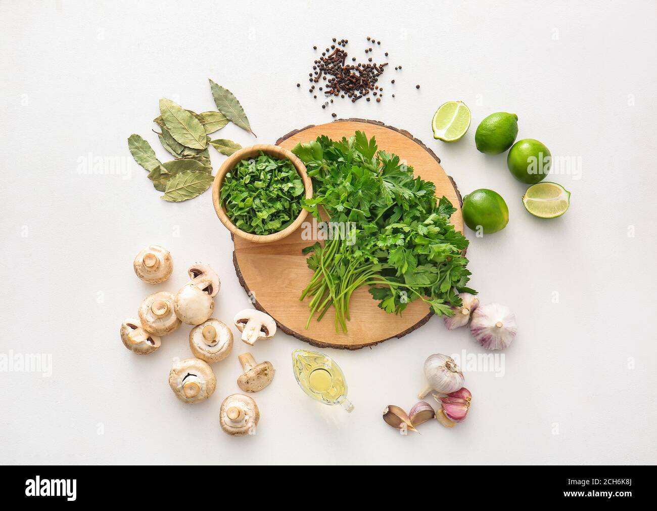 Tavola con prezzemolo fresco, funghi e spezie su sfondo bianco Foto Stock