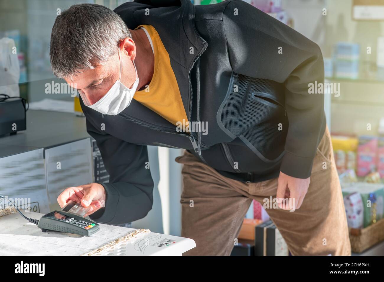 Uomo che paga in negozio con la sua carta di credito. Concetto di pagamento senza contatto. Foto Stock