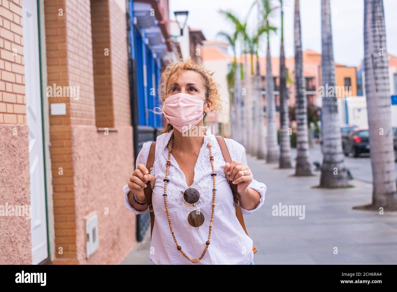Donna all'aperto in città in attività di svago a piedi e. godendo di indossare una maschera di protezione rosa coronavirus - covid-19 e. persone con nuova normalità Foto Stock