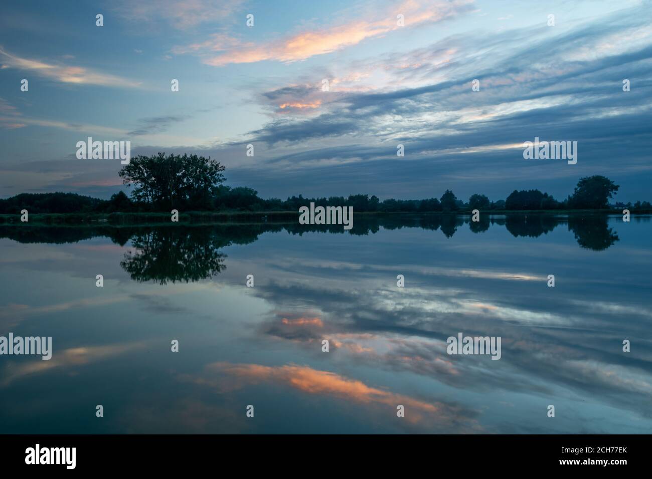 Speculare delle nuvole serali nell'acqua del lago Foto Stock