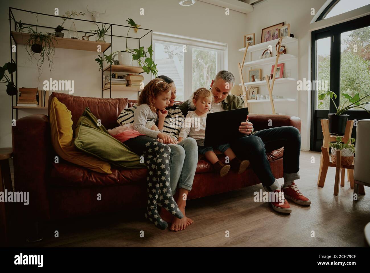 Giovane famiglia con figlia che guarda i video sul computer portatile mentre si rilassa a casa Foto Stock