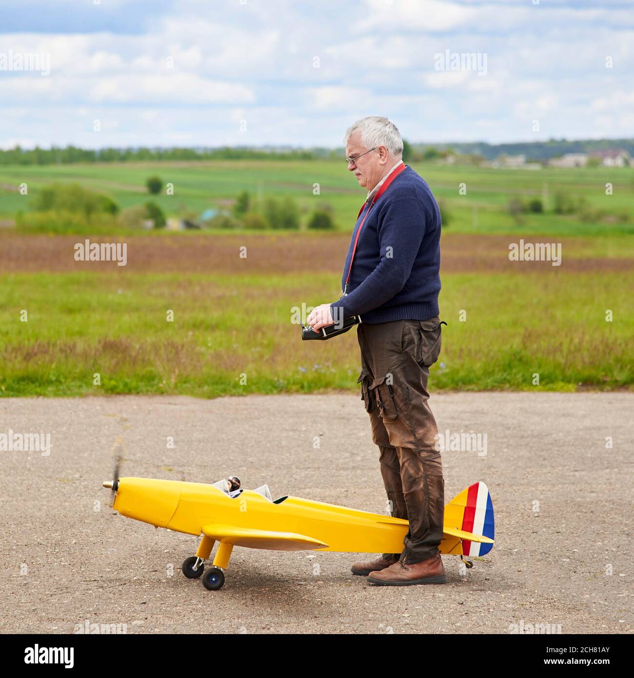 Un uomo anziano lancia un aereo radiocontrollato sulla pista in primavera. Foto Stock