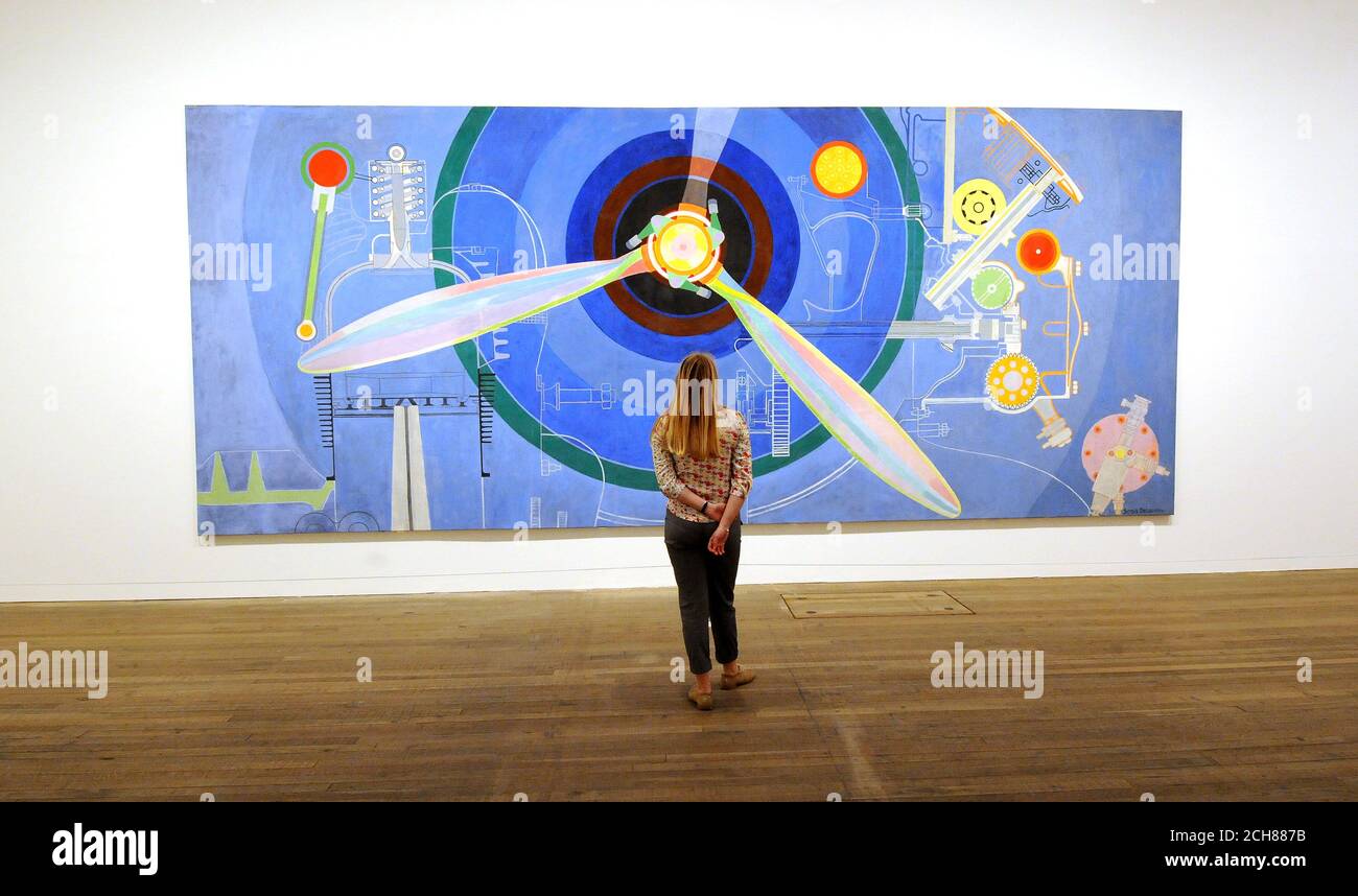 Un dipendente di Tate Modern guarda Propeller (a sinistra, Air Pavillion), dell'artista Sonia Delaunay, che fa parte della EY Exhibition: Sonia Delaunay al Tate Modern di Londra. Foto Stock