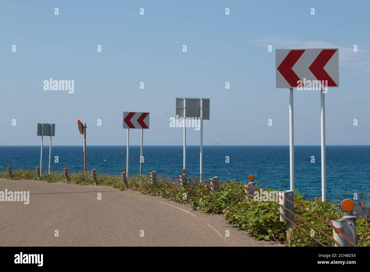 Segnali di avvertimento di curva stretta sulla strada costiera Foto Stock