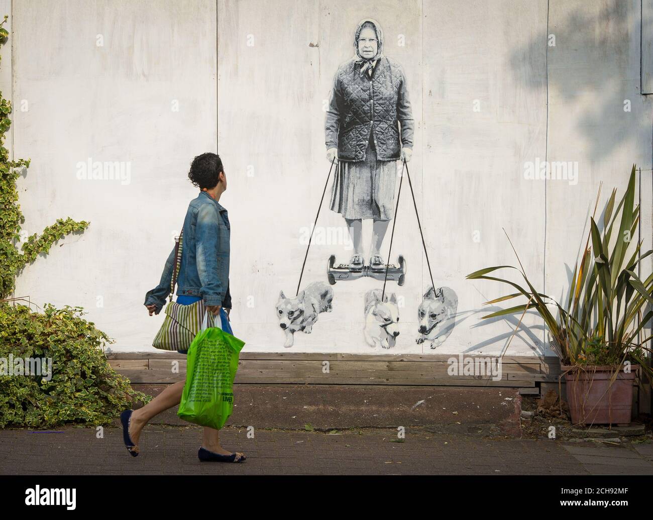 Una donna passa un nuovo murale che mostra la regina Elisabetta II, dal catman dell'artista di strada, a East Dulwich, Londra. Foto Stock