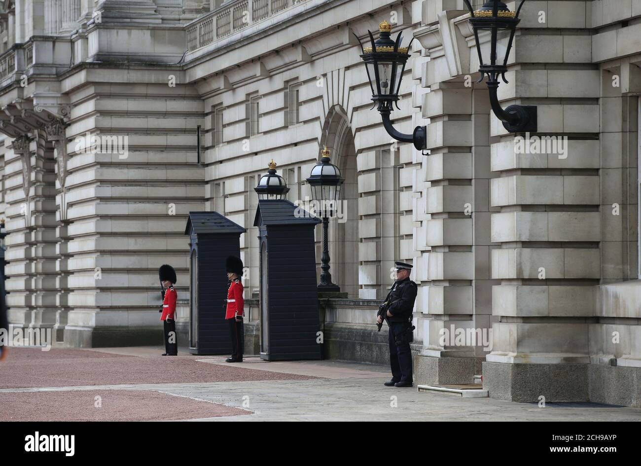 Un ufficiale di polizia armato e soldati delle guardie irlandesi nel piazzale di Buckingham Palace nel centro di Londra. Scotland Yard ha detto che un uomo di 41 anni è stato arrestato dopo aver scalato un muro perimetrale al palazzo mercoledì sera. Foto Stock