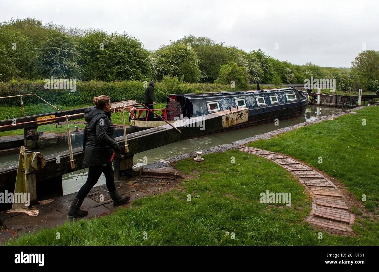 Una barca di canale è navigata attraverso un blocco sul canale Kennett e Avon vicino a Froxfield nel Wiltshire. Foto Stock