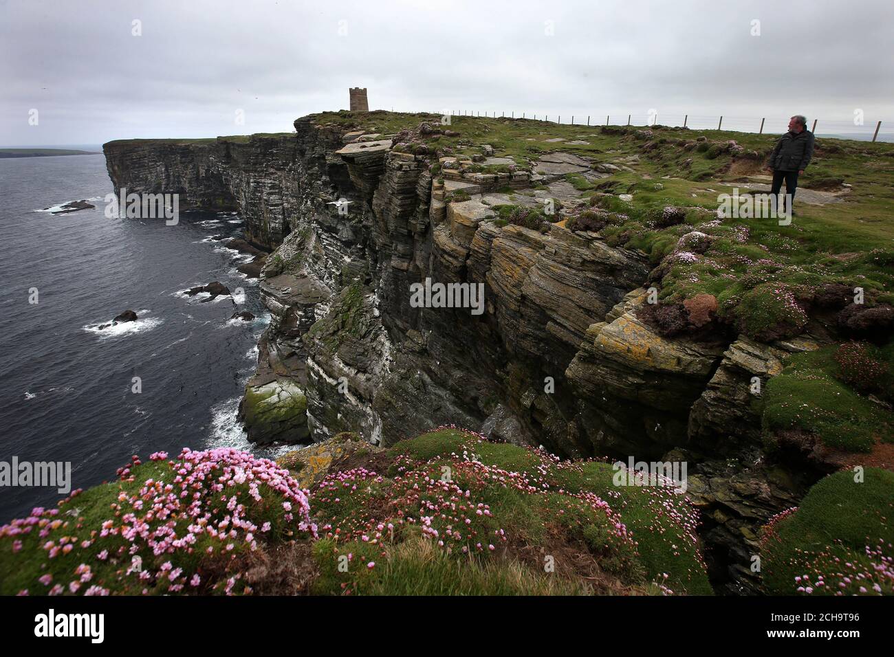 I visitatori camminano lungo le cime delle scogliere alte sopra il mare a Marwick Head in Orkney, dove si erge la torre costruita per onorare la memoria di Lord Kitchener. Foto Stock