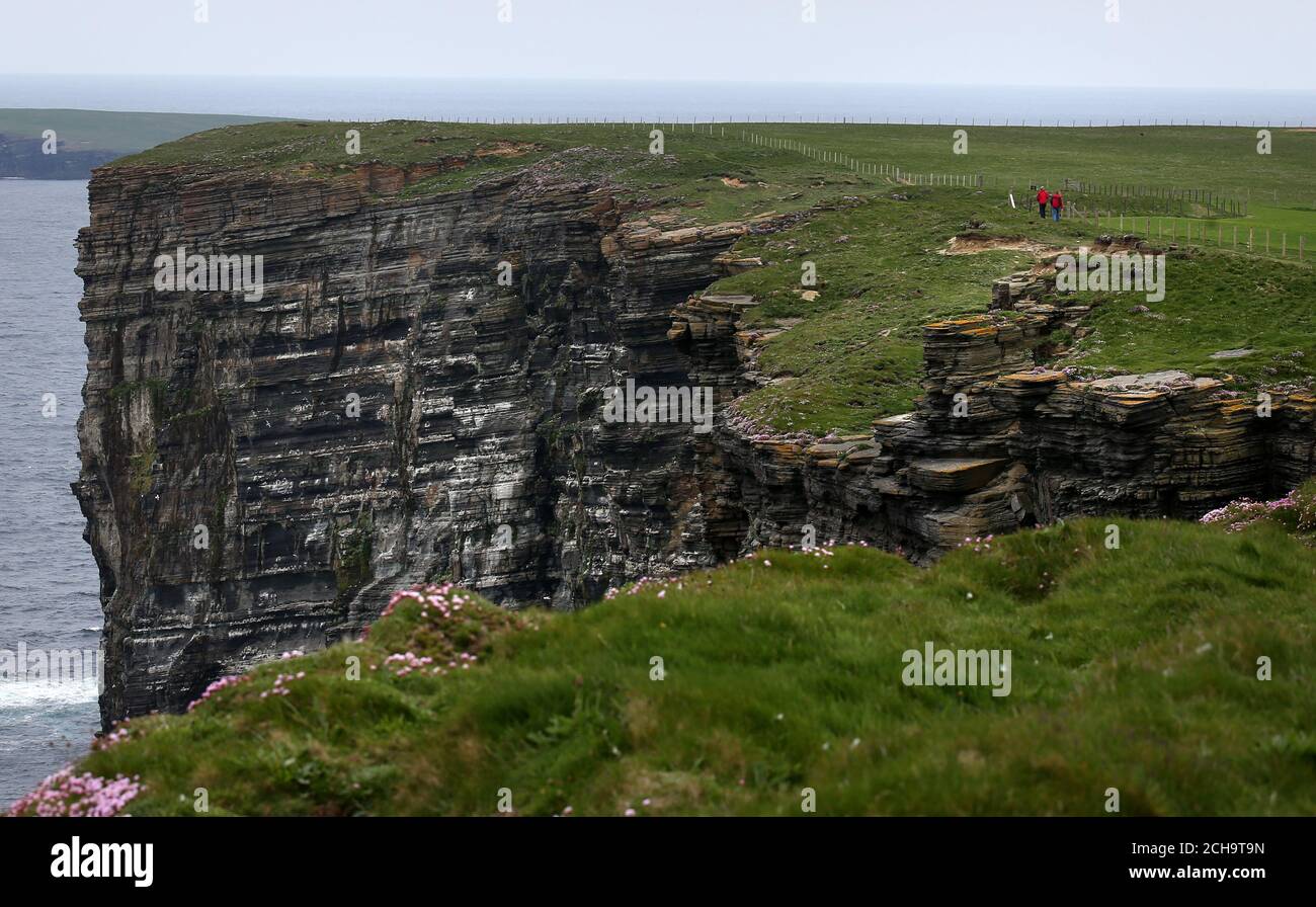 I visitatori camminano lungo le cime delle scogliere alte sopra il mare A Marwick Head in Orkney Foto Stock