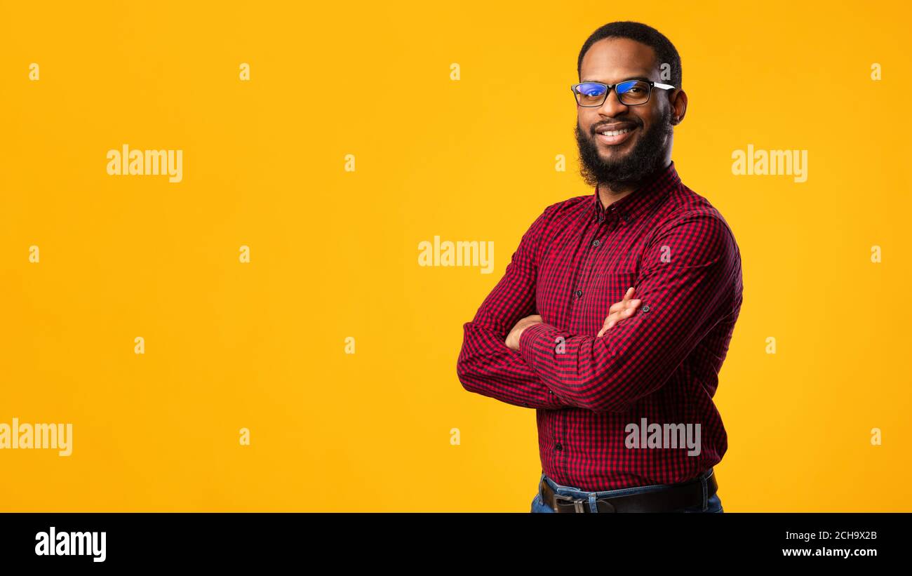 Sorridente afro uomo che posa su sfondo giallo Foto Stock