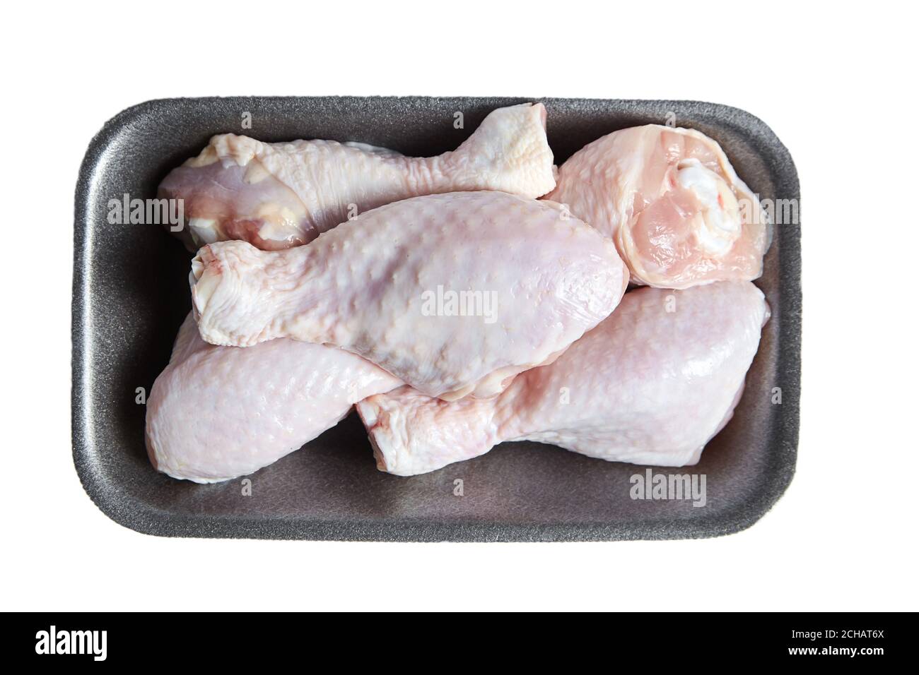 Cosce di pollo non cotte con pelle in un contenitore di plastica grigio. Carne di pollame cruda in un vassoio, isolato su sfondo bianco, vista dall'alto Foto Stock