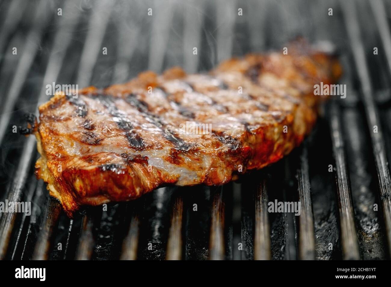 Primo piano di deliziosa bistecca di manzo sulla griglia fiammeggiante. Immagine di alta qualità Foto Stock