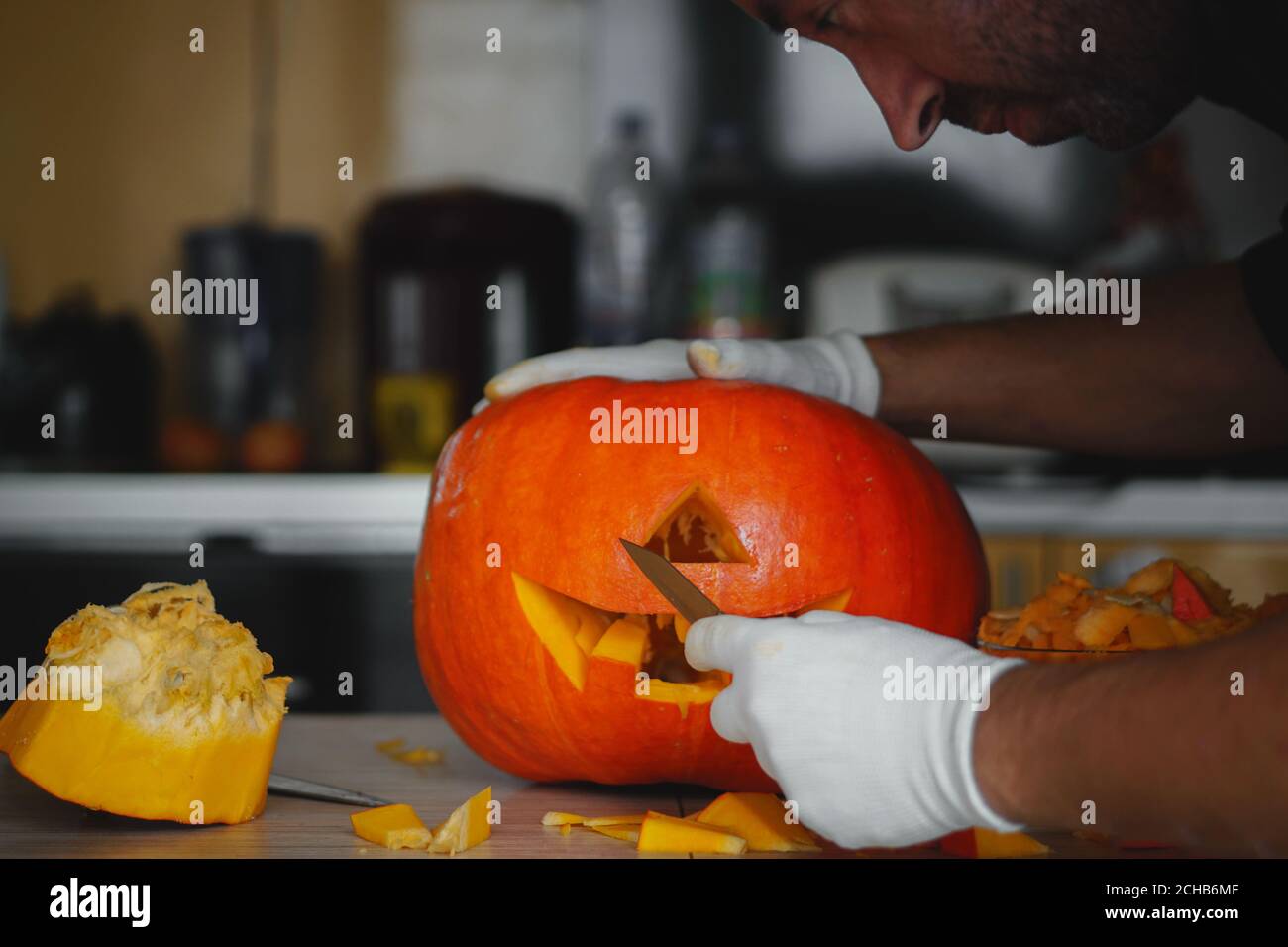 Uomo che fa Halloween testa di zucca jack lanterna su tavolo di legno a casa, closeup. Foto Stock