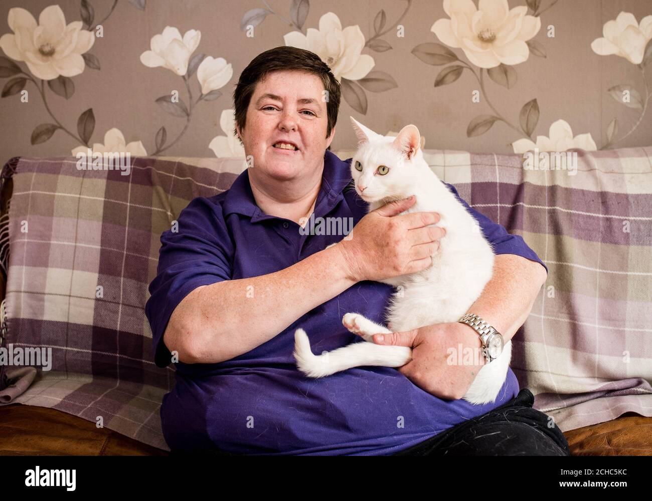 Jackie Kennedy di Poplar, Londra con il suo gatto Lily, una croce siamese bianca britannica, che è stata nominata nella categoria 'Hero Cat' nei Cats Protection National Cat Awards di quest'anno, sponsorizzata da Purina. Foto Stock