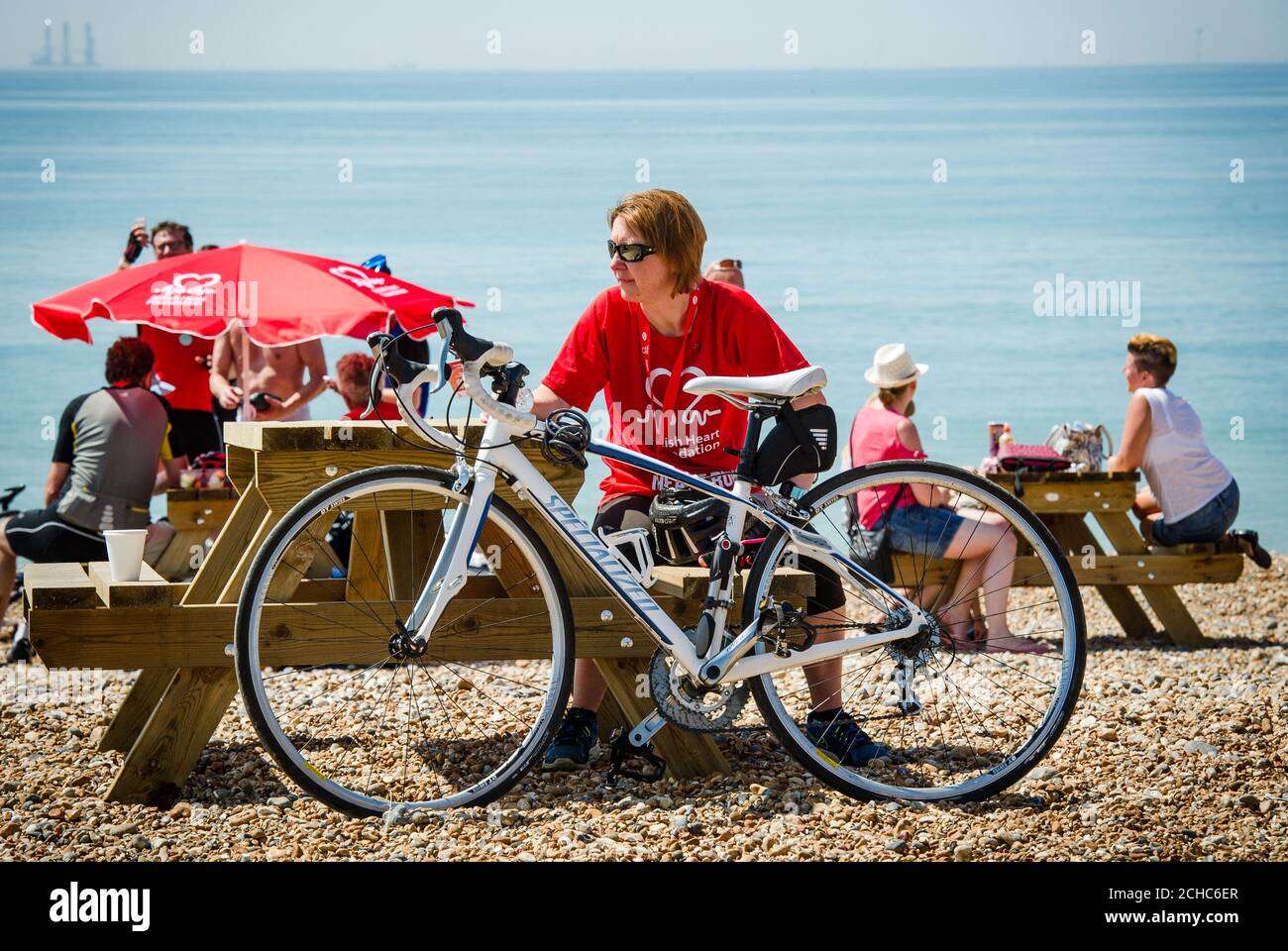 Un ciclista si riposa molto meritato sulla spiaggia di Brighton dopo aver partecipato alla 42nd London to Brighton Bike Ride della British Heart Foundation, sostenuta da Tesco e Jaffa. Foto Stock