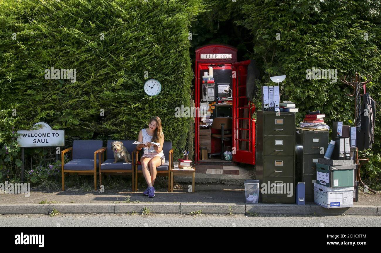 Residente del villaggio, Sophie Pockett ed il suo cane Paddy siedono fuori di un telefono BT box nel villaggio di Saul in Gloucestershire, Che è stato trasformato nel Regno Unito ufficio per Jimmy McGill, il carattere immaginario di Better Call Saul, prima della sua rete prima su BT TV Martedì 27 giugno. Foto Stock