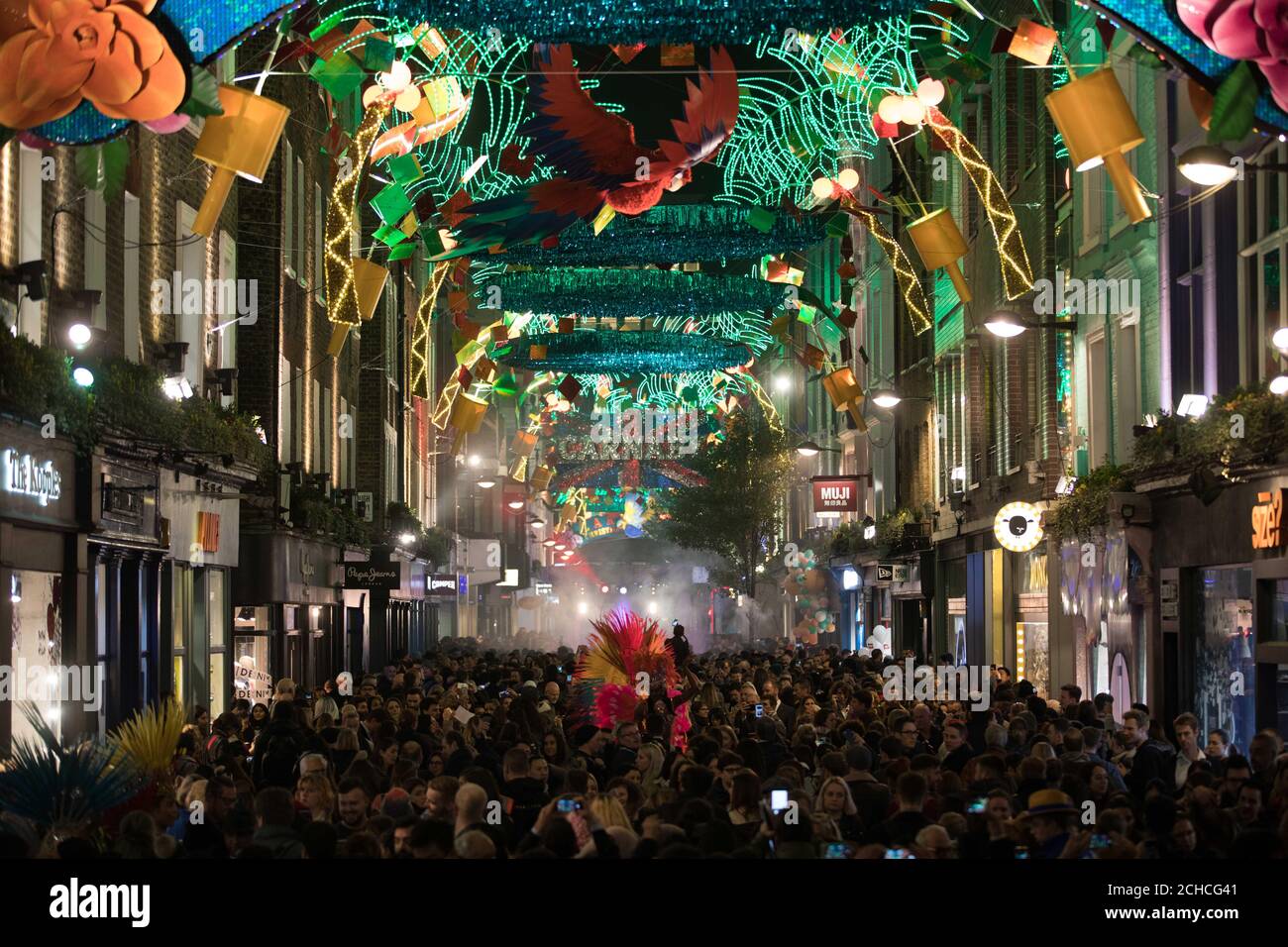 Le folle si riuniscono per l'accensione delle luci di Natale Carnaby a Carnaby, Londra, che presenta un tema di carnevale. Foto Stock