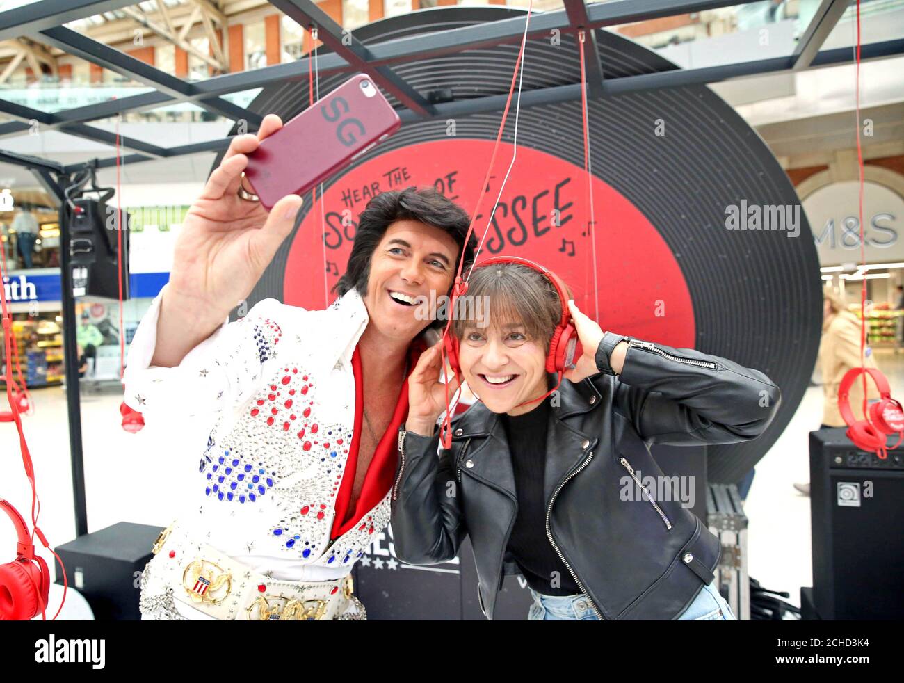 EDITORIALE USE ONLY un Elvis sosia con commuter Shoshana Gillis di Londra, al lancio dell'esperienza 'suoni e suoni del Tennessee', ospitato dal Dipartimento di sviluppo Turistico del Tennessee alla Stazione di Waterloo Londra. Foto Stock