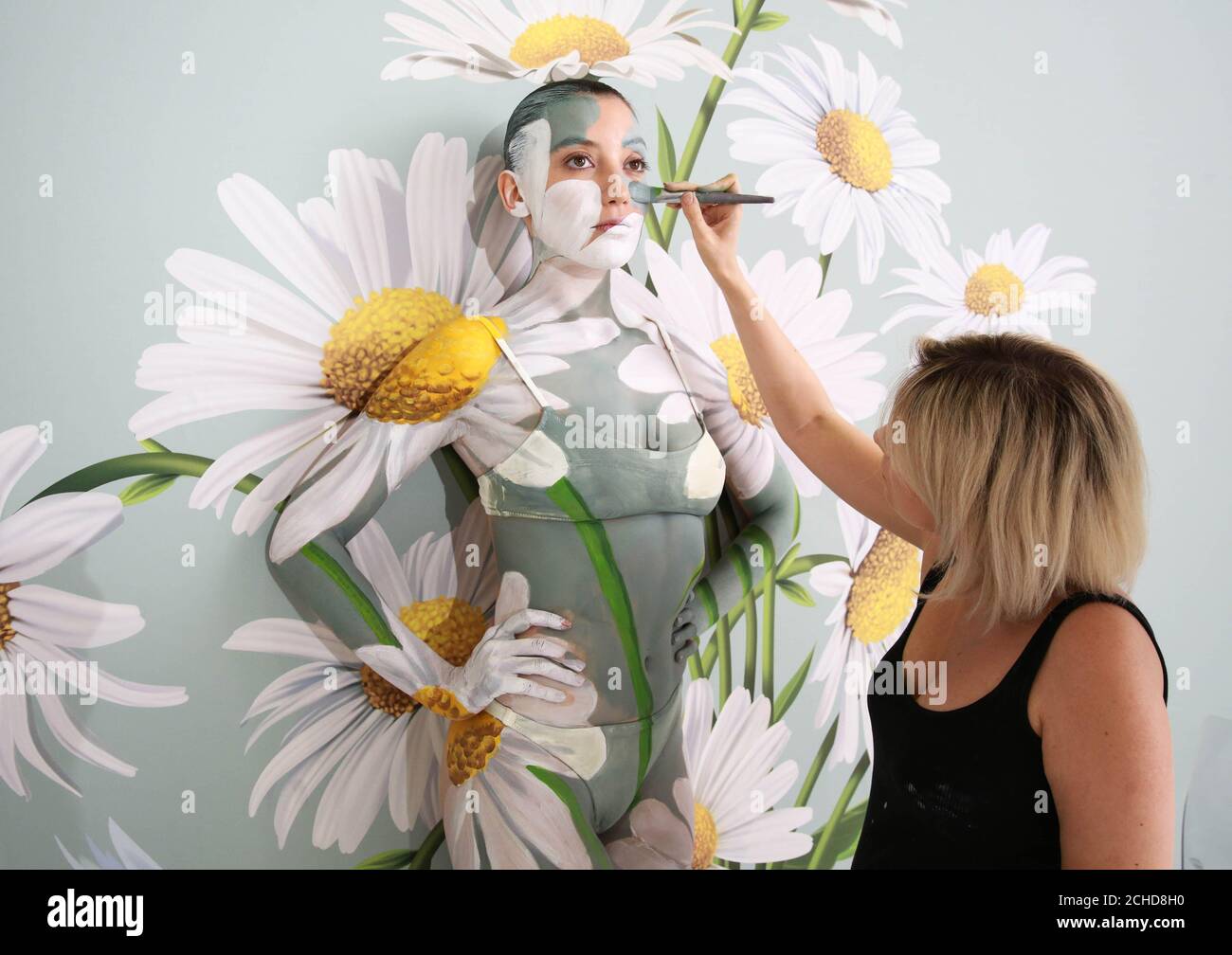SOLO PER USO EDITORIALE Daisy Lowe è stato camuffato in un muro di margherite da Carolyn Roper, il principale artista di body paint al mondo, per mostrare la funzione Ambient Mode del TV Samsung QLED. Il Foto Stock