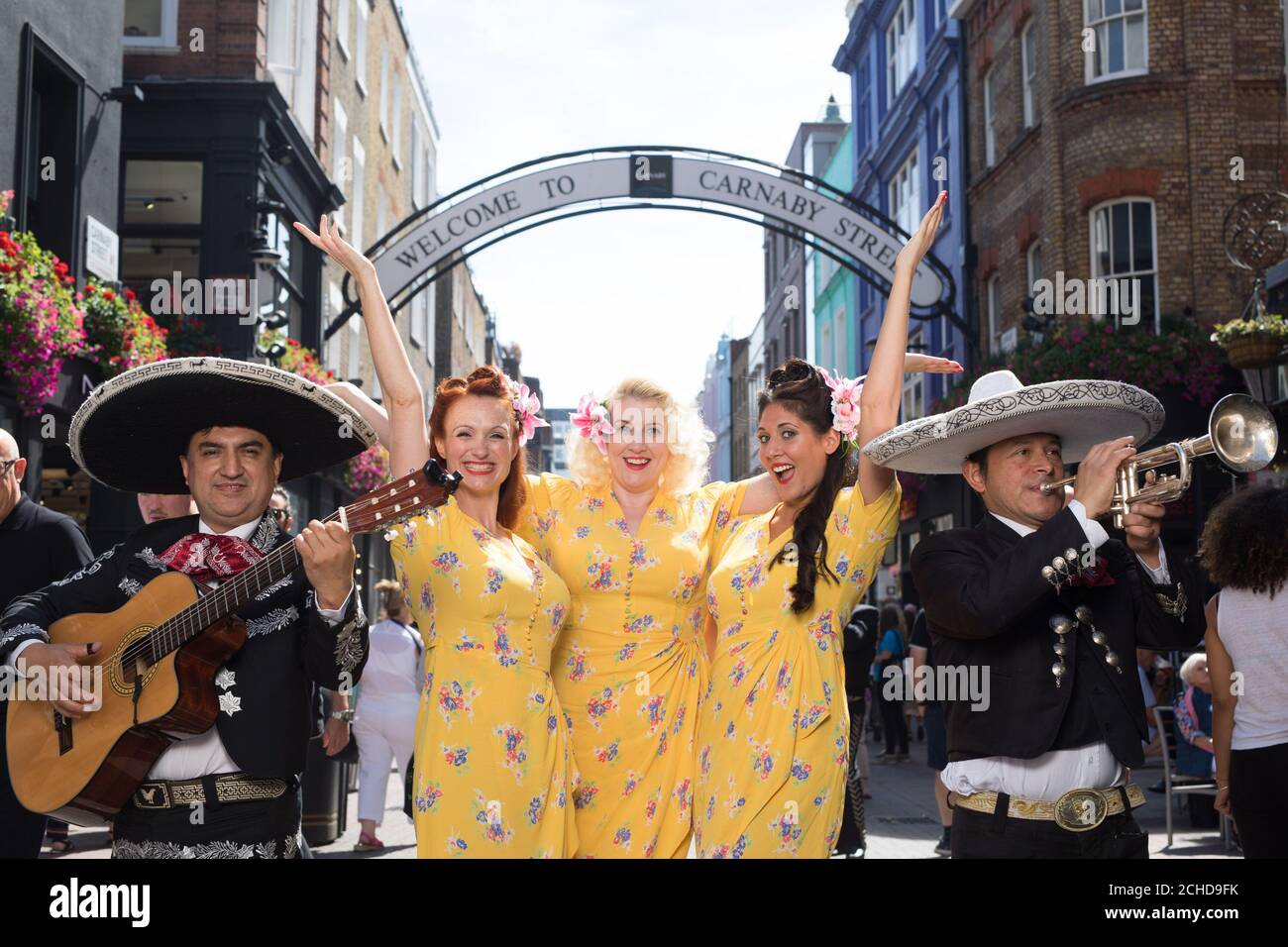 USO EDITORIALE SOLO i cantanti retrò Hotsie Totties da cahots e Mariachi El Mexicano sotto l'arco di Carnaby Street per celebrare il quinto festival annuale di Street food, Carnaby Street Eat. Foto Stock