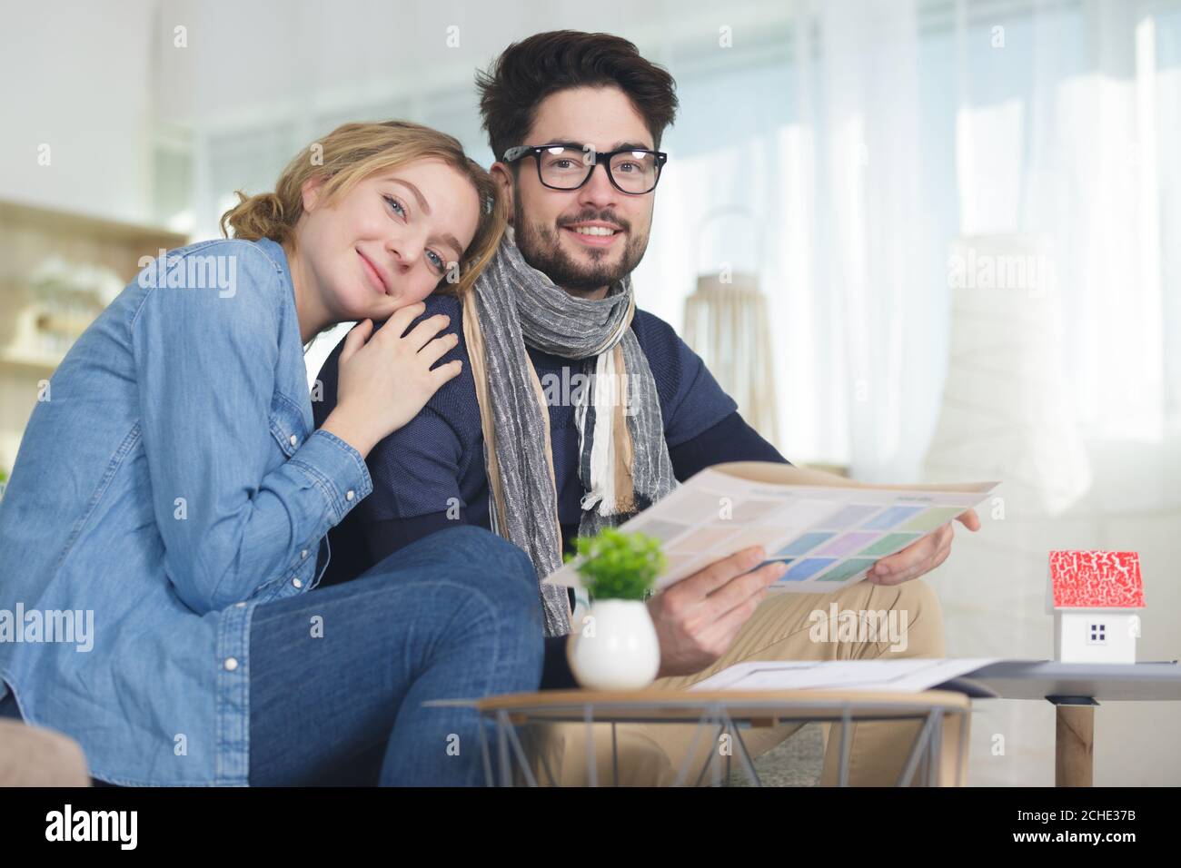 la coppia si è seduta sul divano guardando le carte a colori Foto Stock