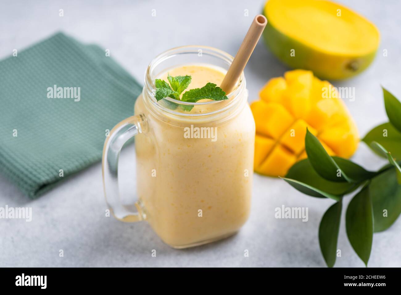 Gustoso frullato vegetariano di mango in un bicchiere con beva di bambù paglia Foto Stock