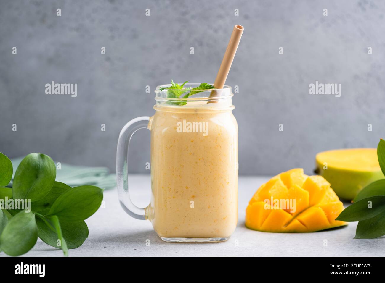 Frullato Mango in vetro su fondo grigio in cemento. Delizioso frullato di mango di frutta tropicale Foto Stock