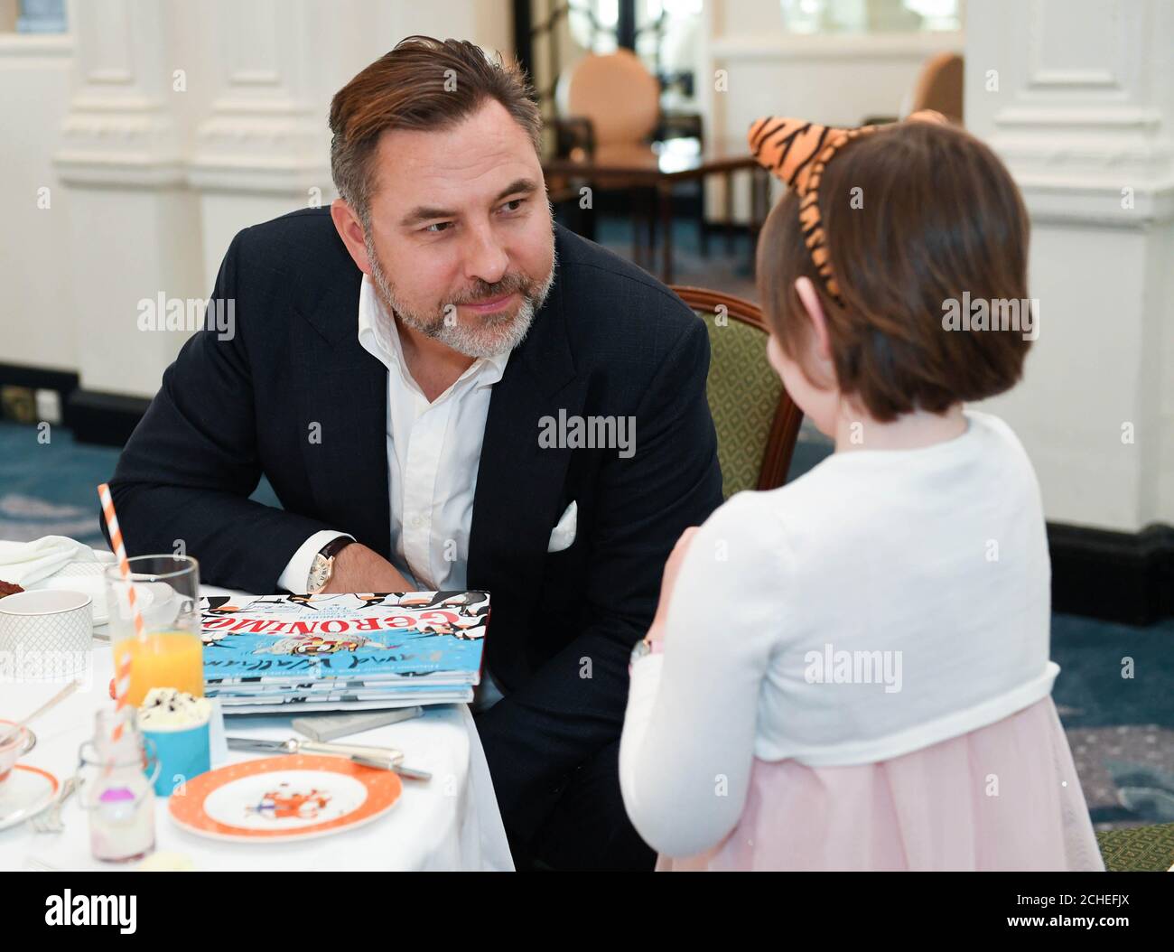 USO EDITORIALE SOLO Violet, di 6 anni, vive con la leucemia, incontra David Walliams che ospita l'ultima esperienza narrativa durante il tè pomeridiano leggendo a cinque bambini augurati e le loro famiglie al Savoy, Londra. Foto Stock