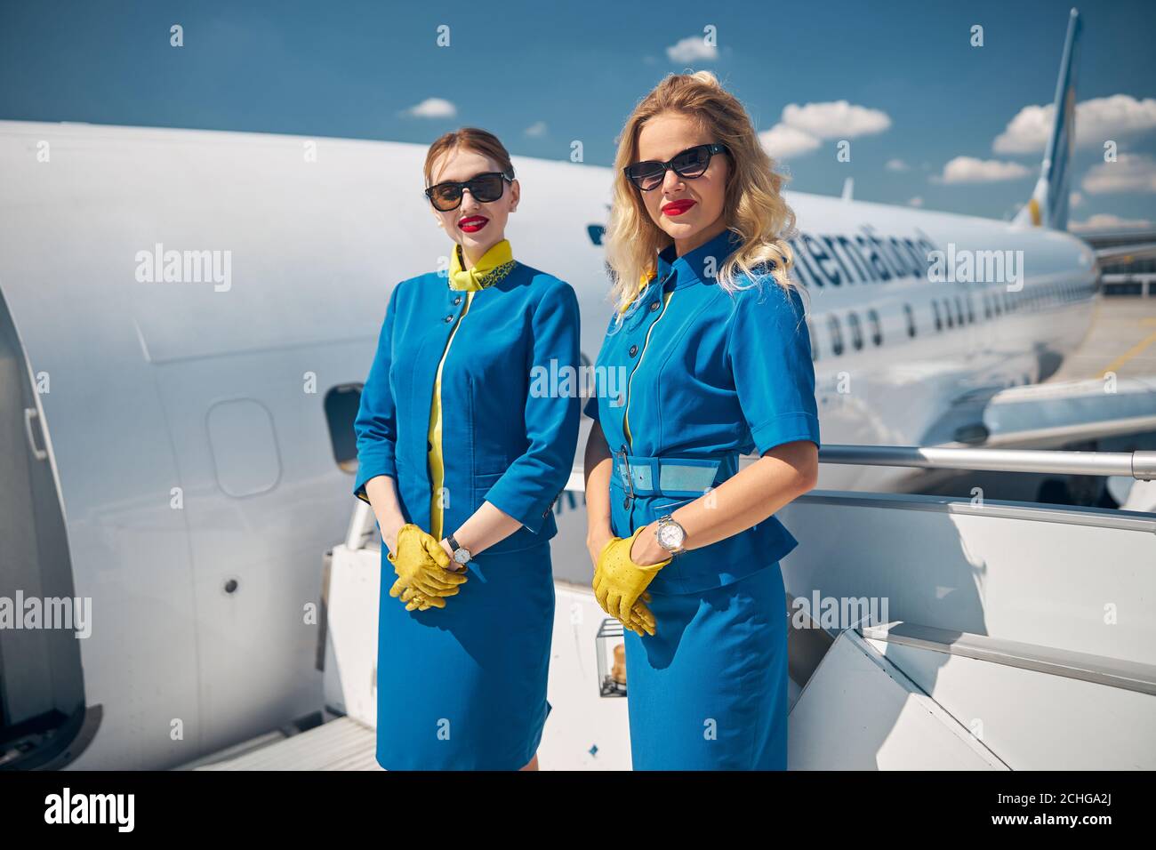 Belle giovani stewardesses in piedi sulle scale dell'aeroplano Foto Stock