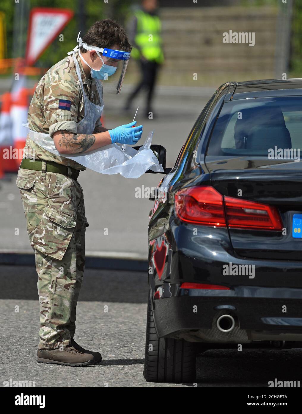 Un soldato tiene un bastoncino presso una stazione di test drive-thrus nel parcheggio del Chessington World of Adventures Resort nel sud-ovest di Londra. Foto Stock