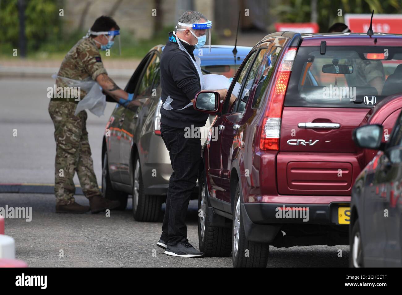 Un soldato e un medico prendono i bastoncini in una stazione di test drive-through per coronavirus nel parcheggio del Chessington World of Adventures Resort, nel sud-ovest di Londra. Foto Stock