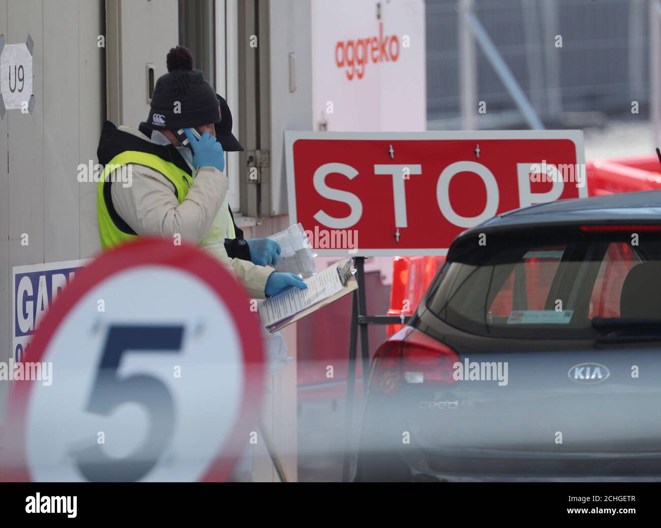 Un membro del personale parla su un telefono cellulare presso una stazione di test drive-thrus nel parcheggio del Twickenham Stadium nel sud-ovest di Londra. Foto Stock