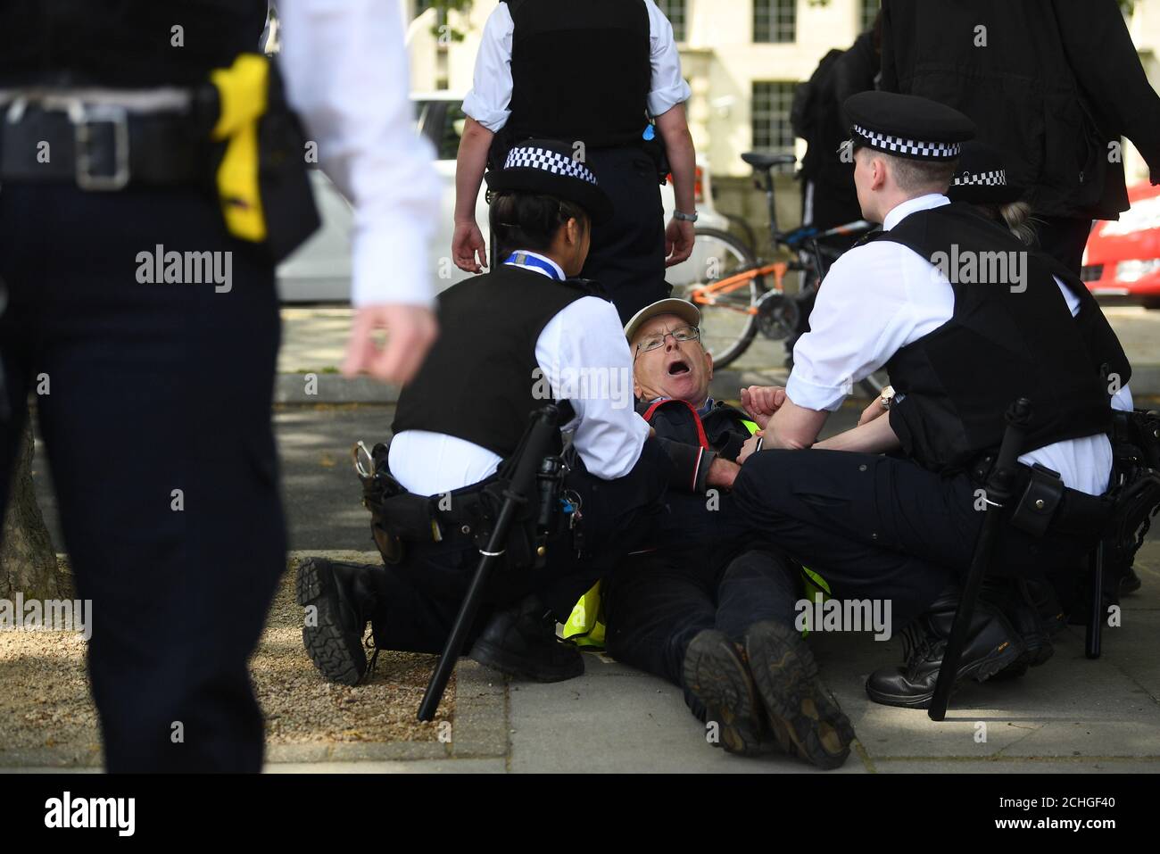 Un uomo è tenuto da ufficiali di polizia durante una protesta contro il blocco Covid-19 fuori New Scotland Yard a Londra. Foto Stock