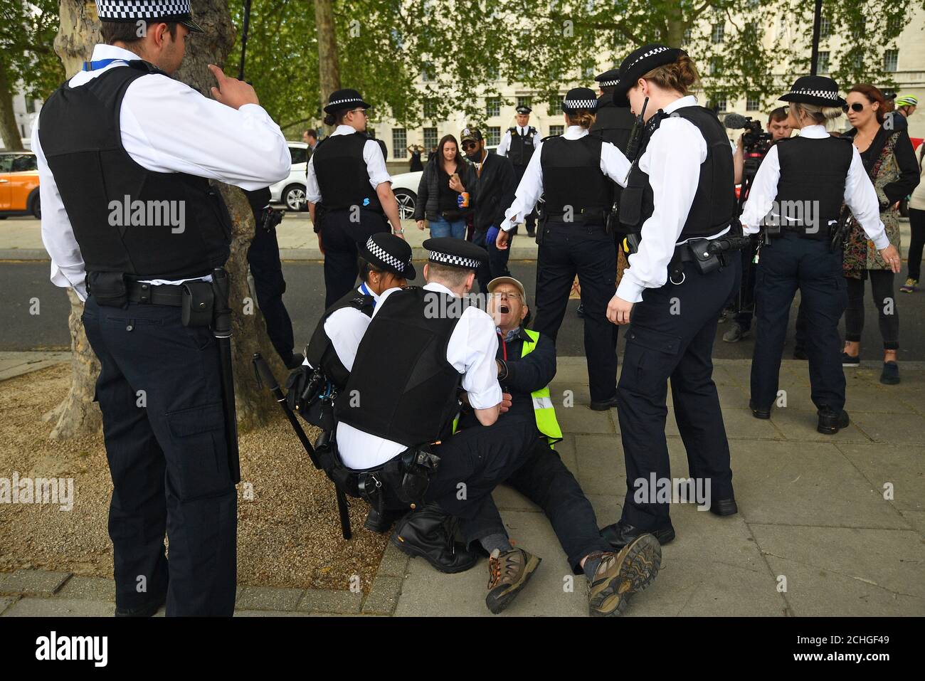 Un uomo è tenuto da ufficiali di polizia durante una protesta contro il blocco Covid-19 fuori New Scotland Yard a Londra. Foto Stock