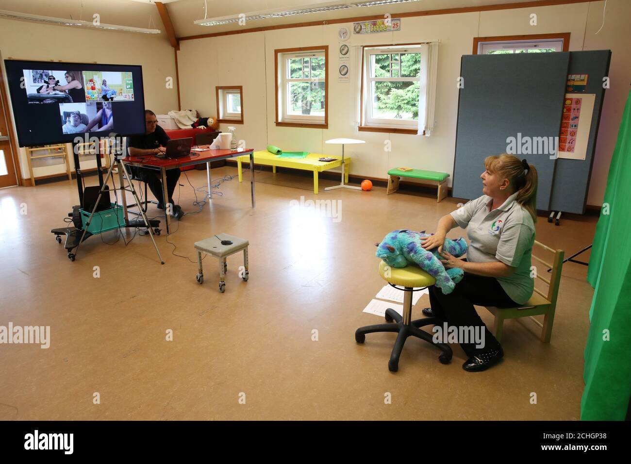 Imbarcato al 0001 lunedì 22 giugno l'insegnante di classe Margaret poli tiene la mascotte Sully del centro mentre partecipa a una sessione di massaggio di storia via Zoom al Craighalbert Center. Queste sessioni si svolgono per offrire un apprendimento misto ai bambini che sono schermati. Gli adattamenti del coronavirus sono stati installati presso lo Scottish Center for Children with Motor Disperiments, Craighalbert Center, Cumbernauld, mentre la Scozia continua gradualmente a sollevare le misure di blocco del coronavirus. Foto Stock