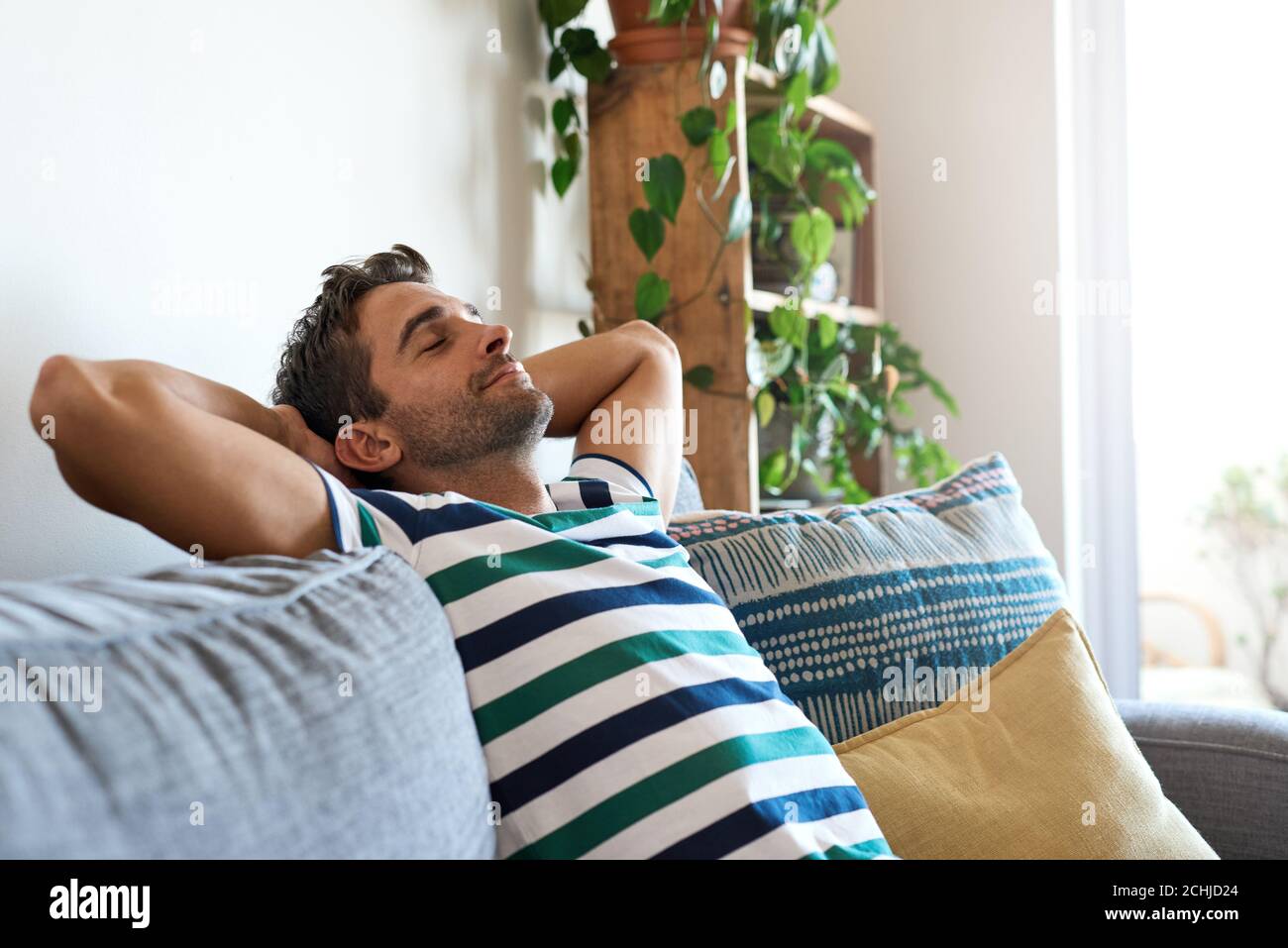 Giovane uomo che si rilassa sul divano del soggiorno a casa Foto Stock