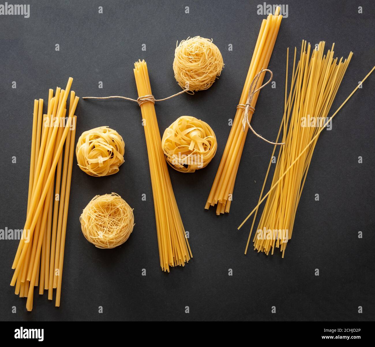 Concetto di cucina della pasta. Spaghetti e tagliatelle di pasta cruda su sfondo nero, vista dall'alto Foto Stock
