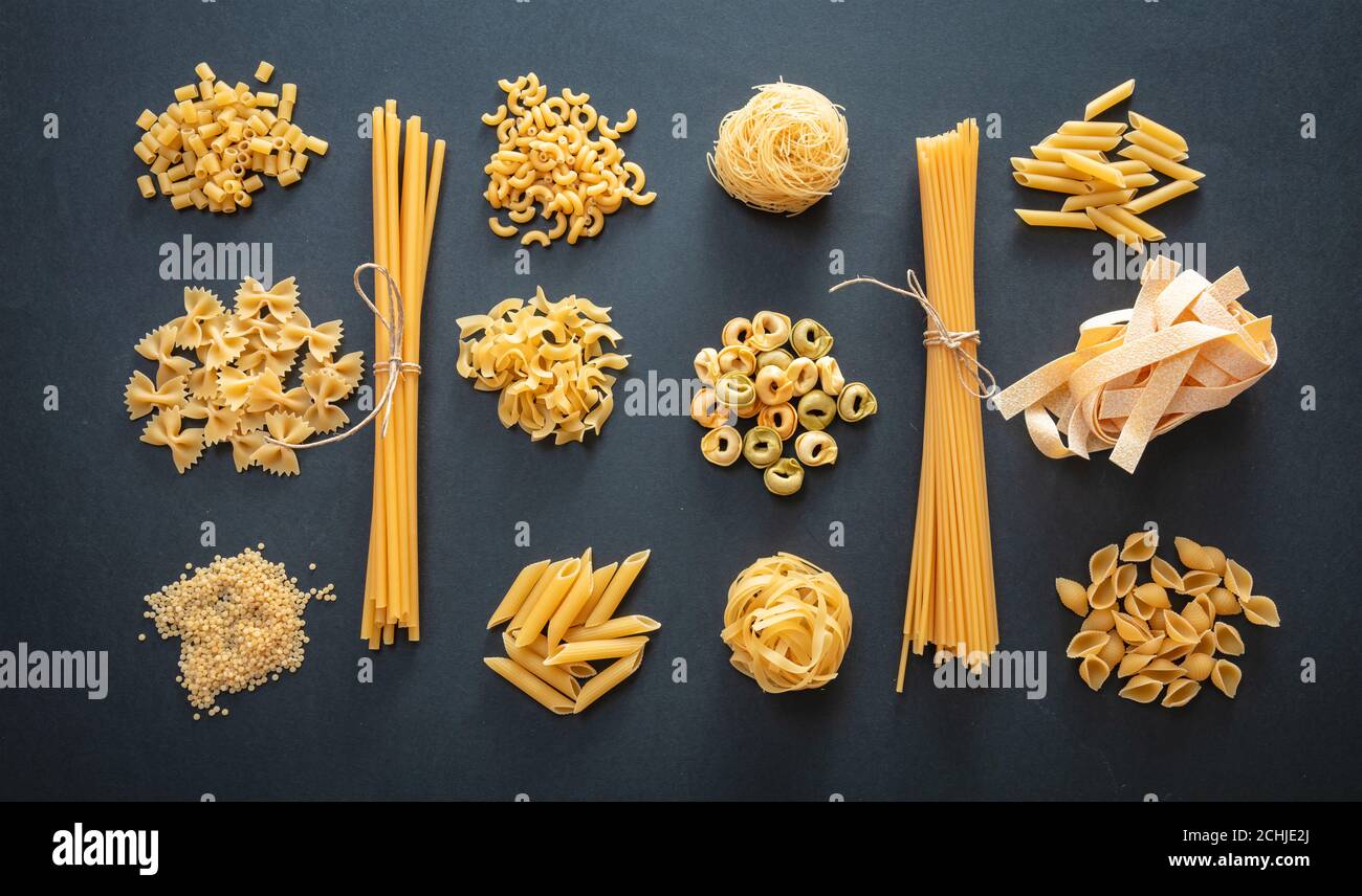 Concetto di cucina della pasta. Varietà di forme di pasta cruda piatte su sfondo nero, vista dall'alto Foto Stock