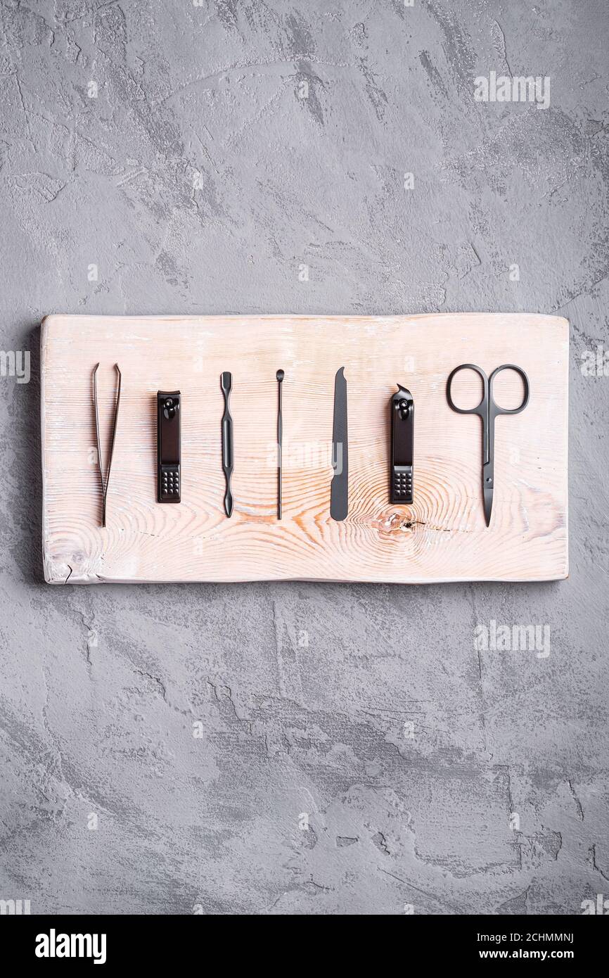 Set di manicure, utensili e accessori per pedicure su tavola di legno, fondo in pietra e calcestruzzo, vista dall'alto Foto Stock