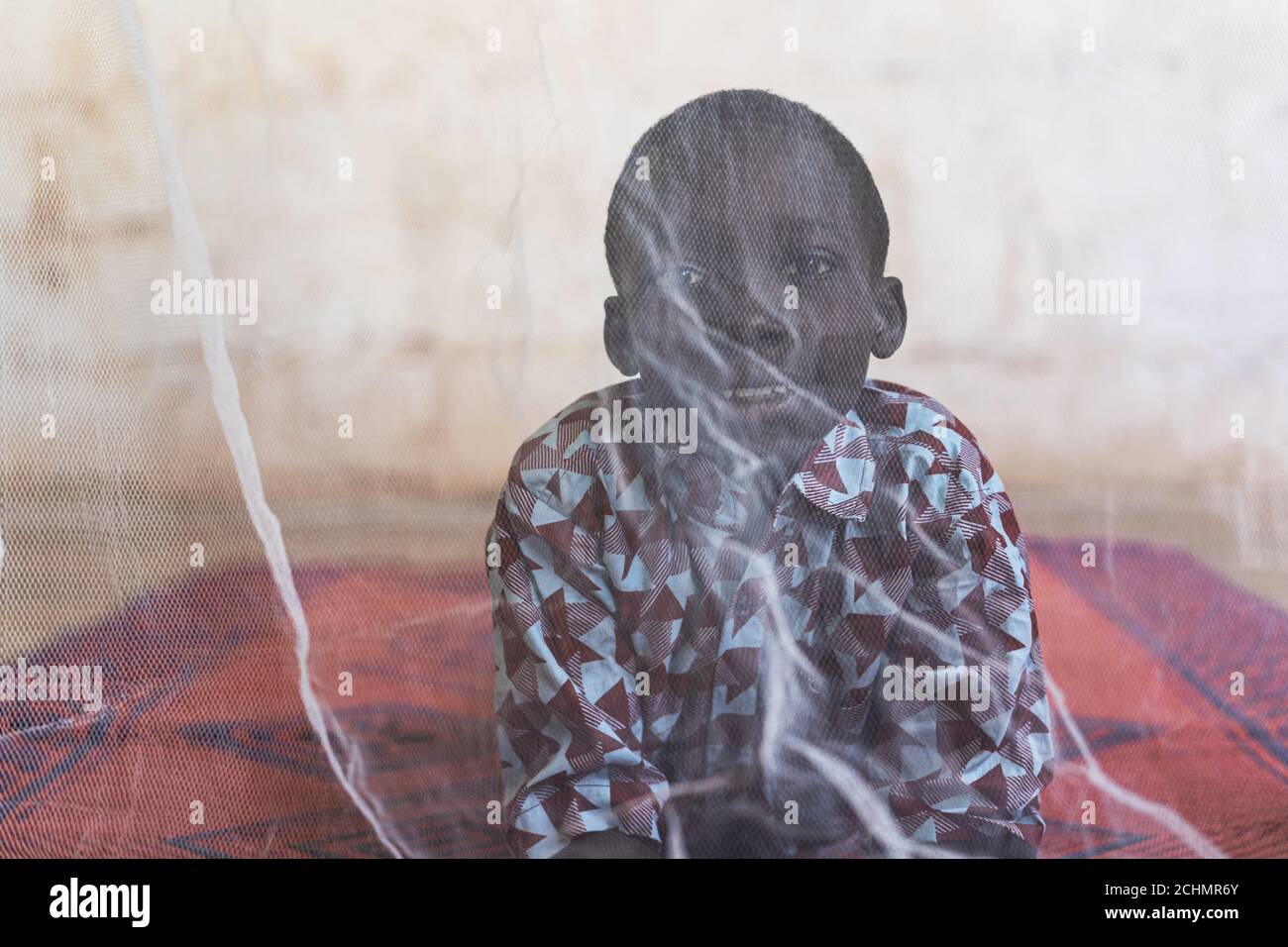 Sorridente Black Boy Portrait con concetto di malaria coperto da Zanzariera Foto Stock