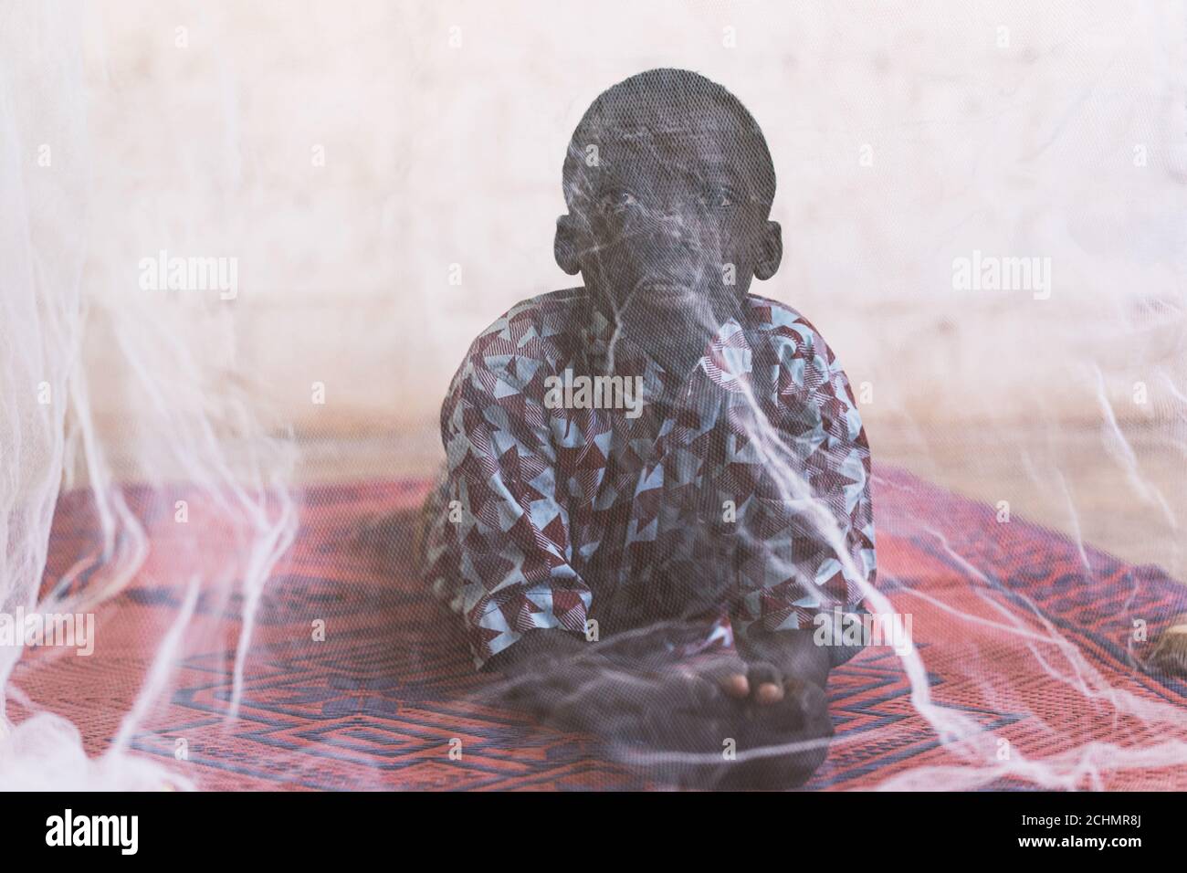 Piccolo ragazzo nero africano con zanzariera per la protezione contro Malaria Foto Stock