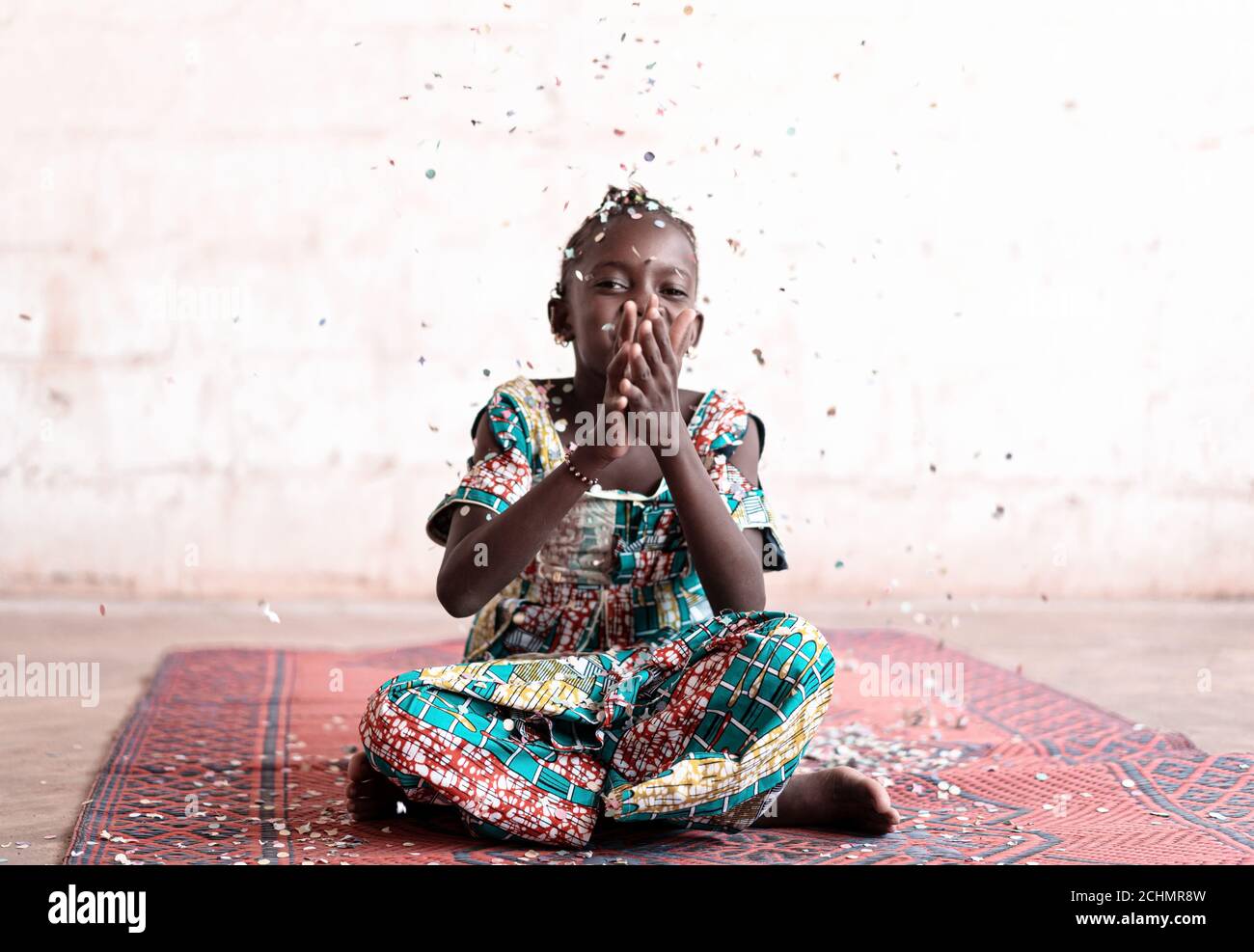 Happy African Young Woman sorridendo alla telecamera divertendosi con confetti party al coperto a casa Foto Stock